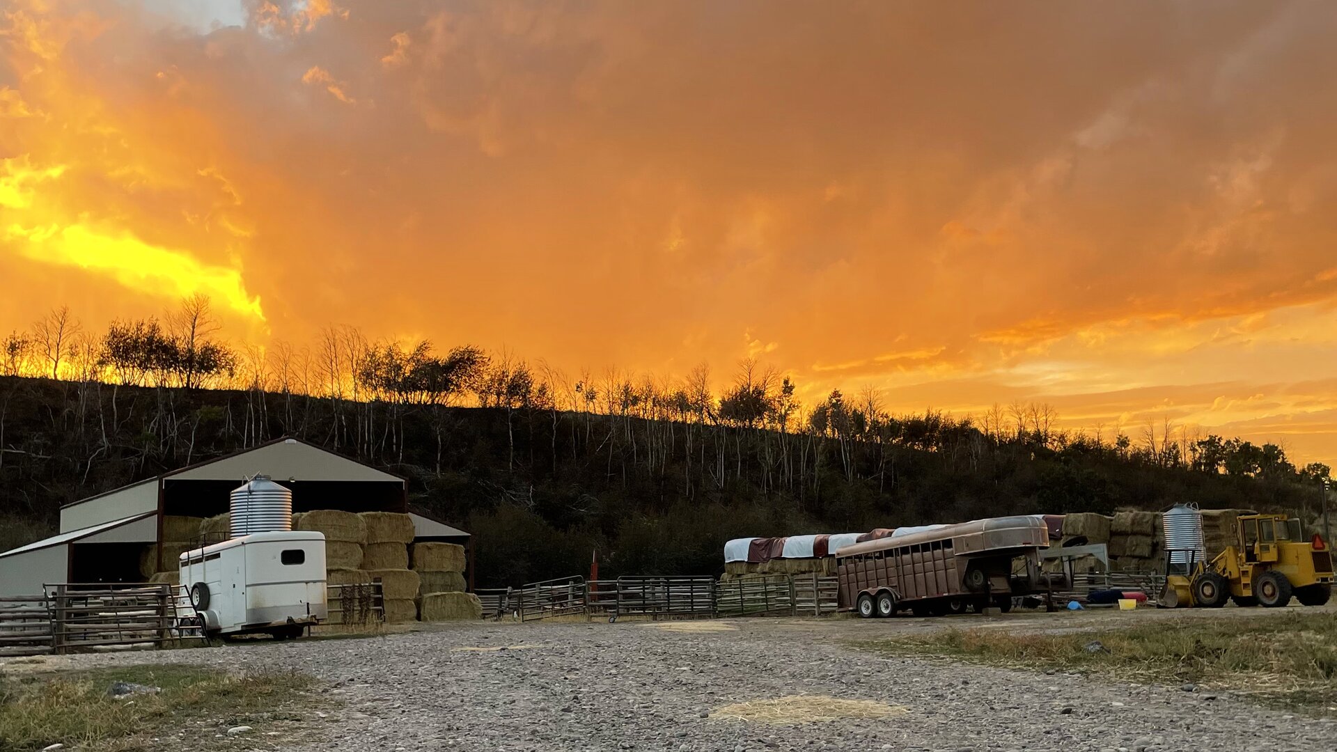 Golden sunset over the RK Livestock barn, hay stacks and trailers